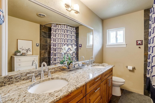 bathroom featuring a textured ceiling, vanity, and toilet