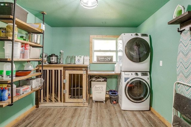 laundry room featuring light wood-type flooring and stacked washer / dryer