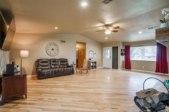 living room with ceiling fan, light wood-type flooring, a textured ceiling, and lofted ceiling