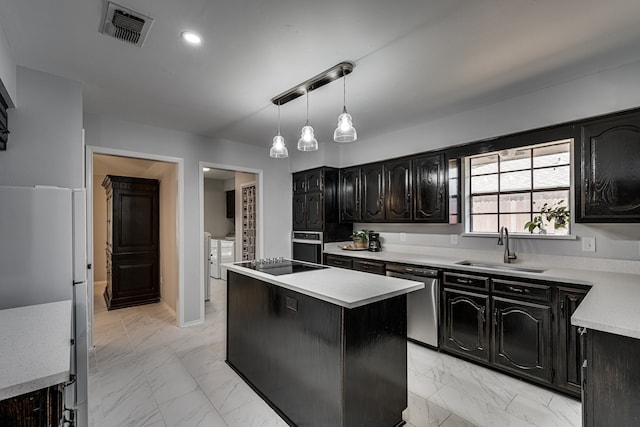 kitchen featuring stainless steel appliances, sink, decorative light fixtures, independent washer and dryer, and a center island