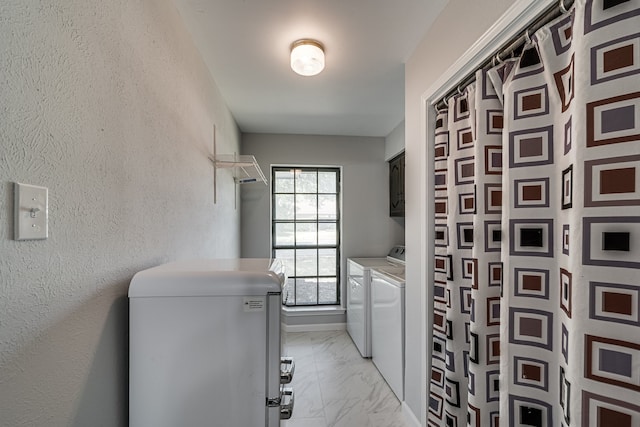 clothes washing area with washer and clothes dryer and cabinets