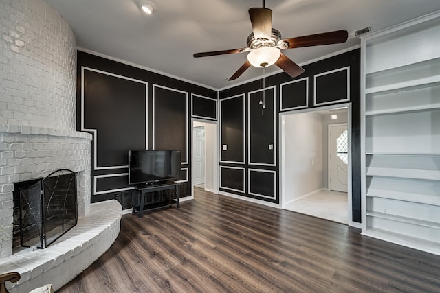 living room featuring ceiling fan, dark hardwood / wood-style flooring, built in features, a fireplace, and ornamental molding