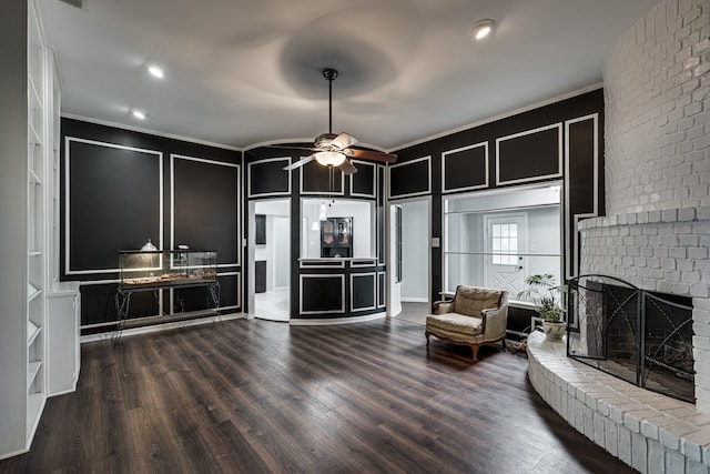 living room with ceiling fan, a fireplace, wood-type flooring, and ornamental molding