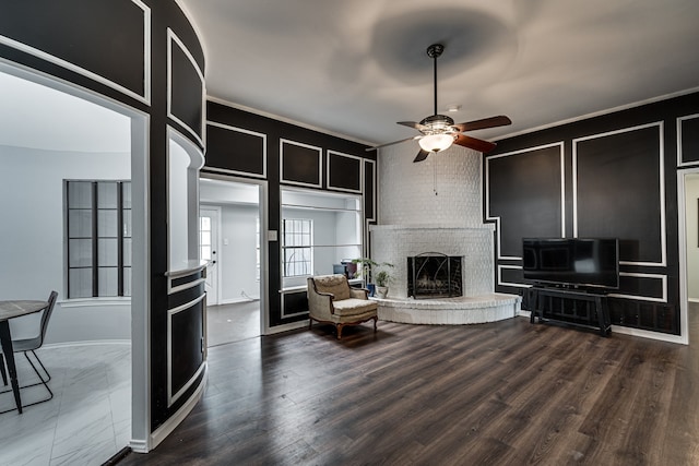 living room featuring ceiling fan, a fireplace, and dark wood-type flooring