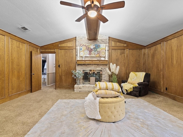 living area with a brick fireplace, wooden walls, lofted ceiling with beams, and light carpet