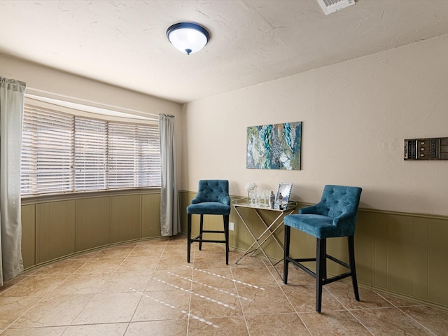 sitting room featuring light tile patterned flooring and wooden walls