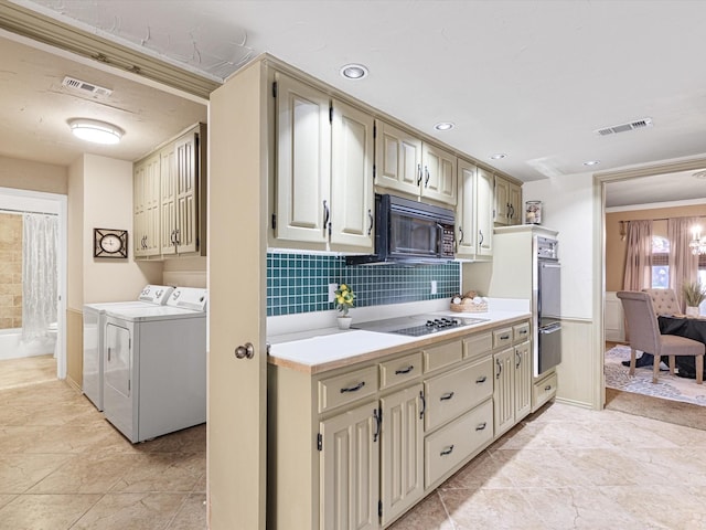 kitchen featuring black appliances, decorative backsplash, separate washer and dryer, and cream cabinetry