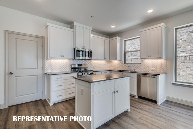 kitchen with white cabinets, decorative backsplash, appliances with stainless steel finishes, and light hardwood / wood-style flooring