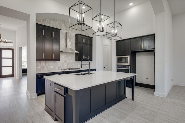 4100 Sandbrock Pkwy, Aubrey, TX 76227 - kitchen featuring a chandelier, wall chimney exhaust hood, stainless steel appliances, a sink, and a kitchen island with sink