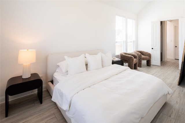 bedroom featuring light wood-type flooring and vaulted ceiling