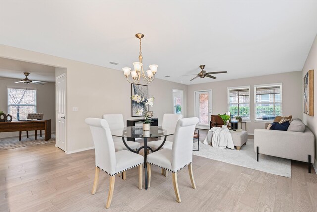 dining room with ceiling fan with notable chandelier and light wood-type flooring