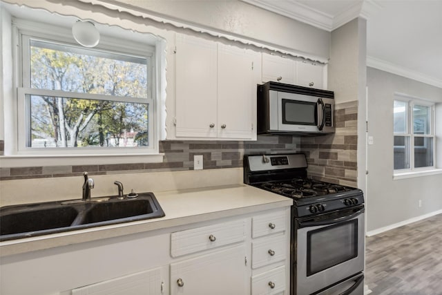 kitchen with white cabinetry, appliances with stainless steel finishes, sink, and ornamental molding