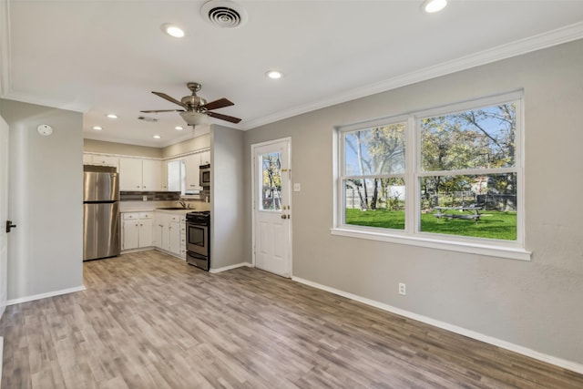 kitchen with sink, light wood-type flooring, ornamental molding, stainless steel appliances, and white cabinets