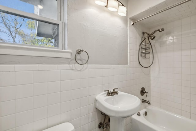 full bathroom featuring tile walls, sink, tiled shower / bath combo, and toilet