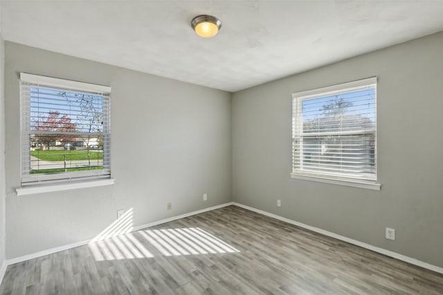 empty room with hardwood / wood-style flooring and a healthy amount of sunlight