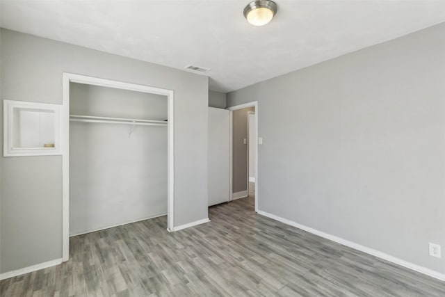 unfurnished bedroom with light wood-type flooring and a closet