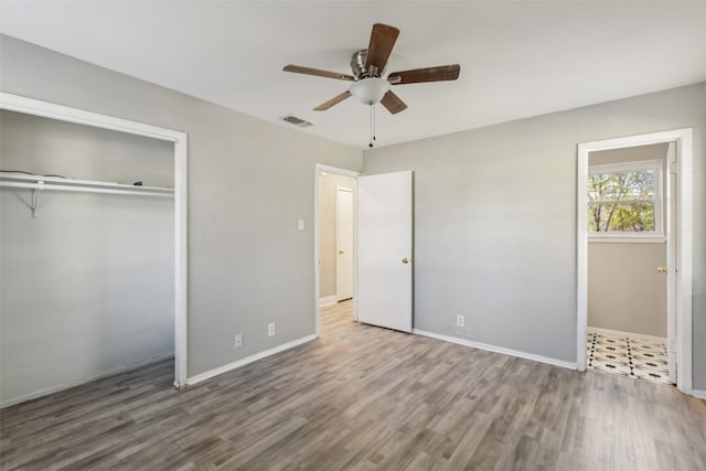 unfurnished bedroom with hardwood / wood-style flooring, ceiling fan, and a closet