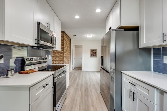 kitchen featuring decorative backsplash, appliances with stainless steel finishes, a textured ceiling, light hardwood / wood-style flooring, and white cabinetry