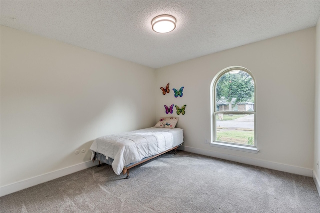 carpeted bedroom featuring a textured ceiling and multiple windows