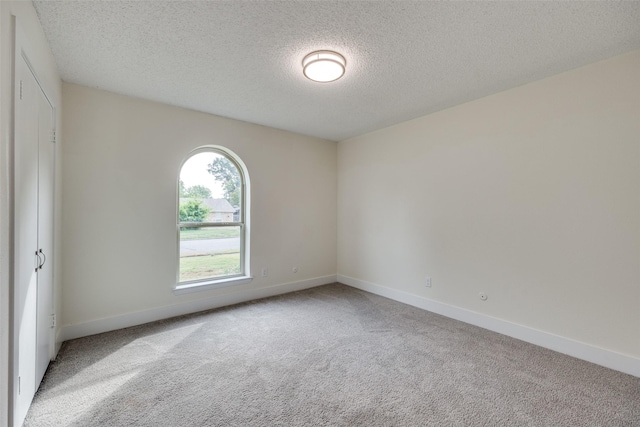 carpeted empty room featuring a textured ceiling