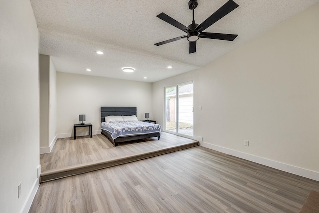 bedroom with ceiling fan, wood-type flooring, and a textured ceiling