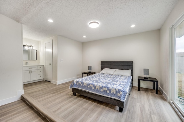 bedroom featuring a textured ceiling, connected bathroom, and light hardwood / wood-style floors