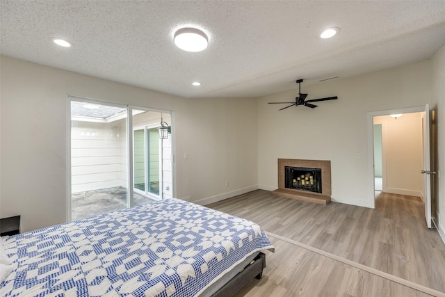 bedroom with access to exterior, a textured ceiling, light hardwood / wood-style flooring, and ceiling fan