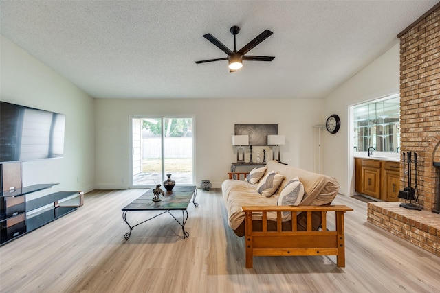 living room with a textured ceiling, light wood-type flooring, ceiling fan, and lofted ceiling