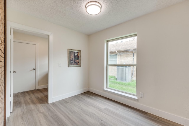 empty room with a textured ceiling and light hardwood / wood-style flooring