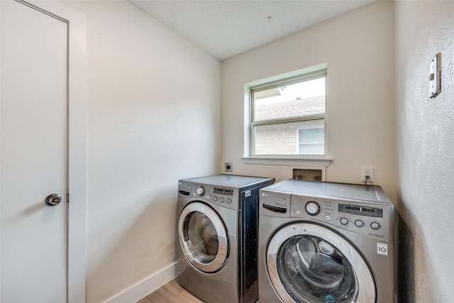 laundry room with a textured ceiling, washing machine and dryer, and light hardwood / wood-style floors