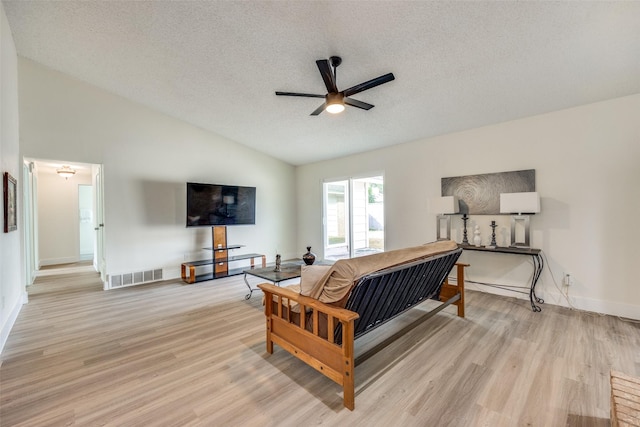 living room featuring a textured ceiling, light wood-type flooring, high vaulted ceiling, and ceiling fan