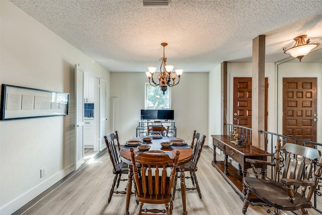 dining room featuring light hardwood / wood-style floors, a textured ceiling, and a chandelier