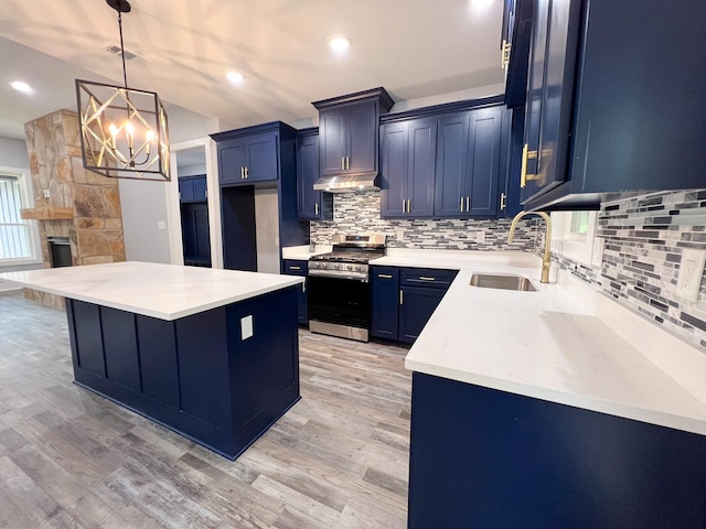 kitchen with stainless steel range with gas cooktop, sink, decorative light fixtures, light hardwood / wood-style floors, and a chandelier