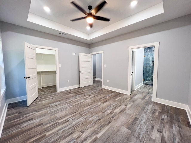 unfurnished bedroom featuring a raised ceiling, ceiling fan, and dark hardwood / wood-style floors