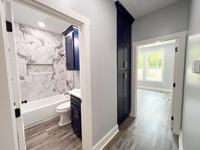 full bathroom featuring vanity, wood-type flooring, tiled shower / bath combo, and toilet