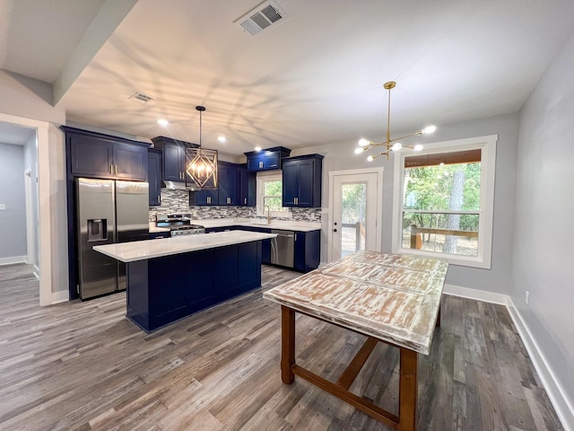 kitchen featuring hardwood / wood-style floors, an inviting chandelier, blue cabinets, decorative light fixtures, and stainless steel appliances