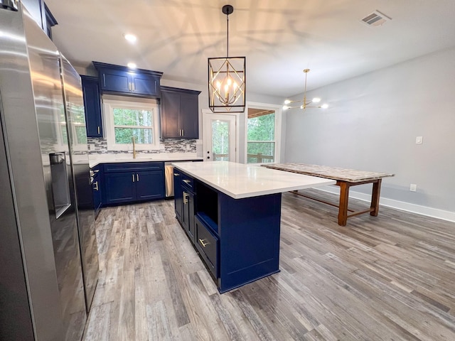 kitchen featuring stainless steel fridge, blue cabinets, a healthy amount of sunlight, and wood-type flooring