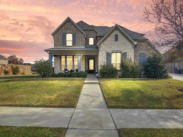 french provincial home with covered porch and a yard