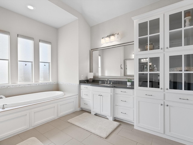 bathroom with a washtub, vanity, and tile patterned floors