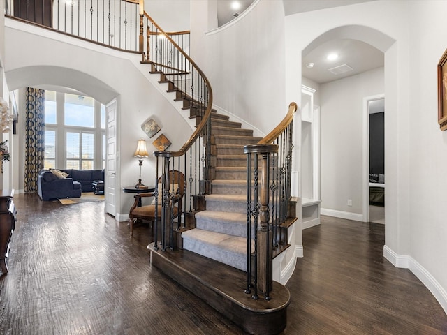 staircase with a high ceiling and hardwood / wood-style flooring