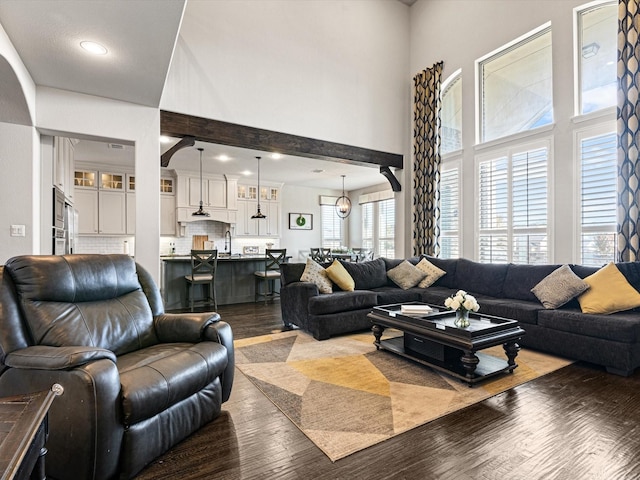 living room with a high ceiling, sink, and wood-type flooring