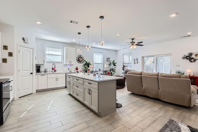 kitchen featuring plenty of natural light, a kitchen island, white cabinetry, and hanging light fixtures