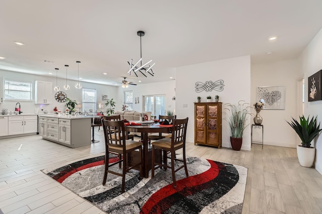 dining space with ceiling fan, light hardwood / wood-style flooring, and sink