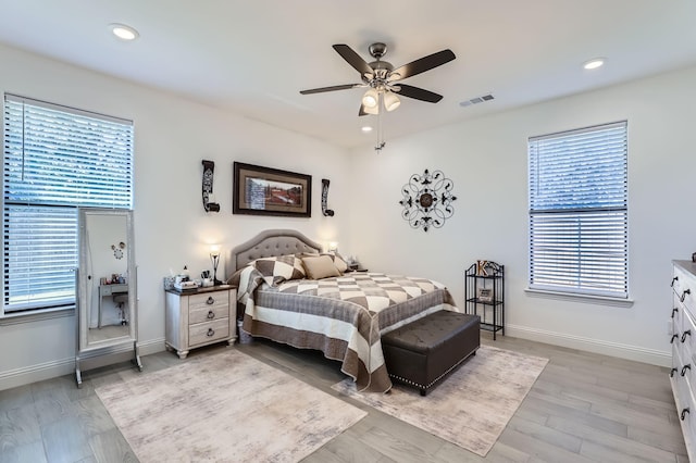 bedroom with multiple windows, ceiling fan, and light hardwood / wood-style floors