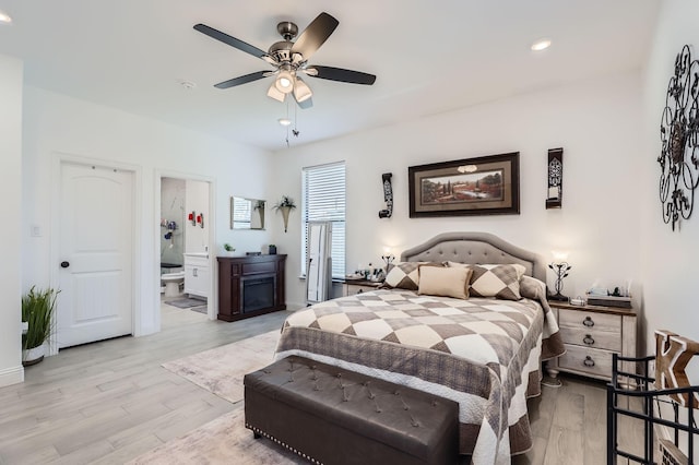 bedroom featuring ceiling fan, connected bathroom, and light hardwood / wood-style flooring