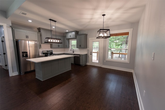 kitchen with gray cabinetry, stainless steel appliances, and hanging light fixtures