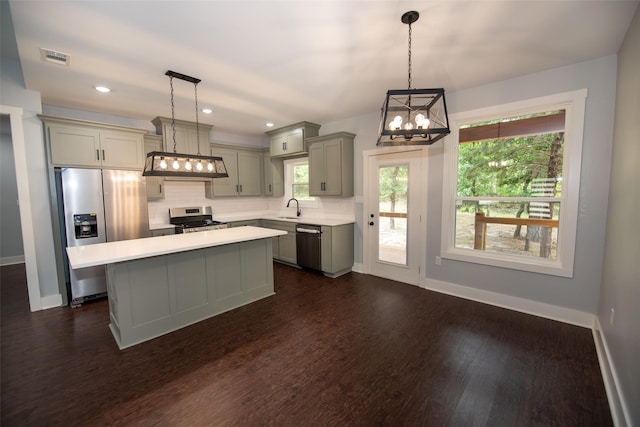 kitchen featuring appliances with stainless steel finishes, a center island, decorative light fixtures, and sink