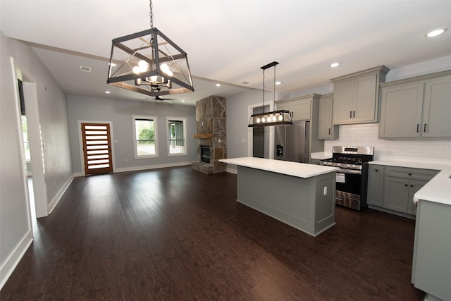 kitchen with gray cabinetry, hanging light fixtures, a stone fireplace, and stainless steel appliances