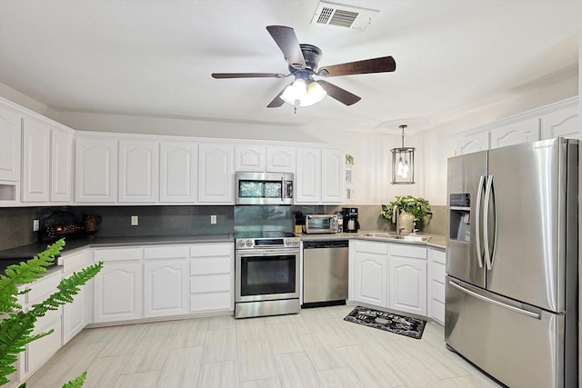 kitchen featuring white cabinets, appliances with stainless steel finishes, backsplash, and pendant lighting