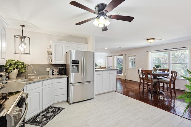 kitchen with white cabinetry, hanging light fixtures, backsplash, kitchen peninsula, and appliances with stainless steel finishes